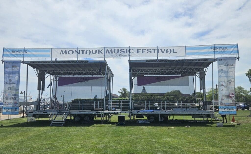 A temporary stage rental service set up in the grass for an outdoor event at the Montauk Music Festival in Long Island, New York