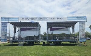 A temporary stage rental service set up in the grass for an outdoor event at the Montauk Music Festival in Long Island, New York